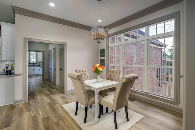 dining space featuring a notable chandelier, crown molding, hardwood / wood-style floors, and sink