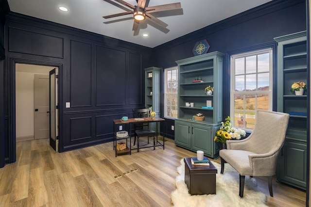 living area featuring ornamental molding, ceiling fan, and light wood-type flooring