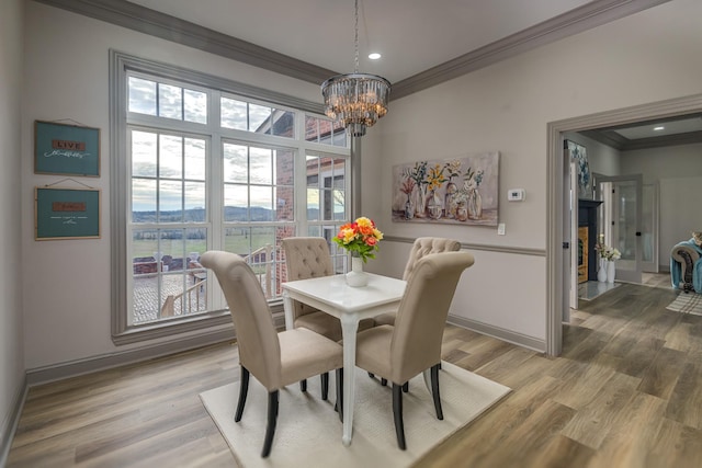 dining space with hardwood / wood-style floors, crown molding, and a chandelier