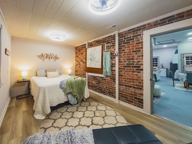 bedroom with brick wall and light hardwood / wood-style floors