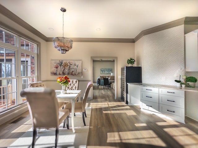 dining room featuring ornamental molding, an inviting chandelier, and dark hardwood / wood-style flooring