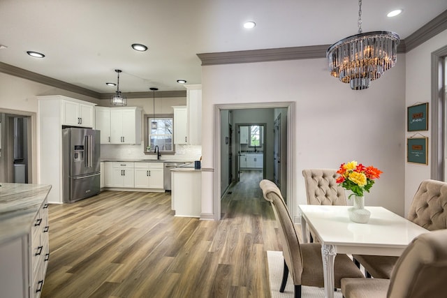 kitchen featuring pendant lighting, crown molding, hardwood / wood-style flooring, appliances with stainless steel finishes, and white cabinets