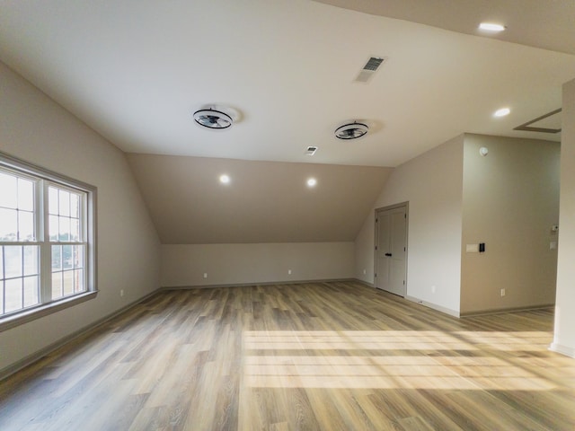 additional living space featuring light hardwood / wood-style floors and vaulted ceiling