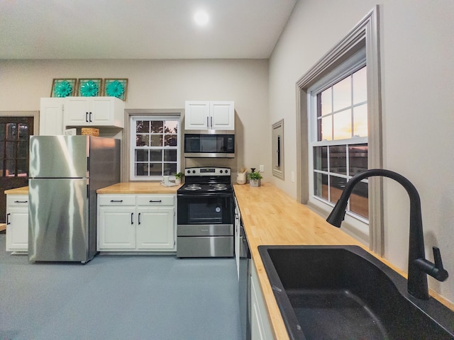 kitchen featuring stainless steel appliances, white cabinetry, sink, and wooden counters