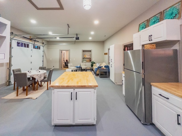 kitchen featuring stainless steel fridge, a kitchen island, white cabinets, and wood counters