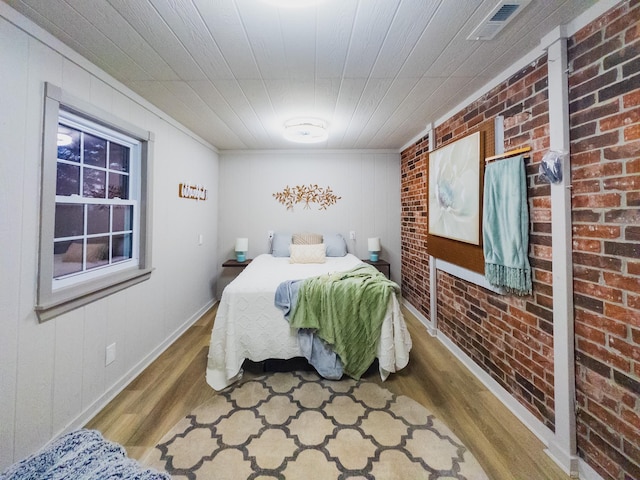bedroom with brick wall and wood-type flooring