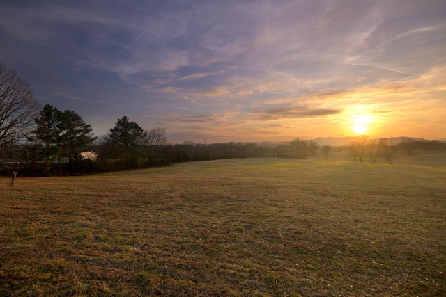 yard at dusk featuring a rural view
