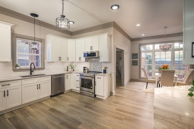 kitchen with white cabinetry, appliances with stainless steel finishes, decorative light fixtures, and sink