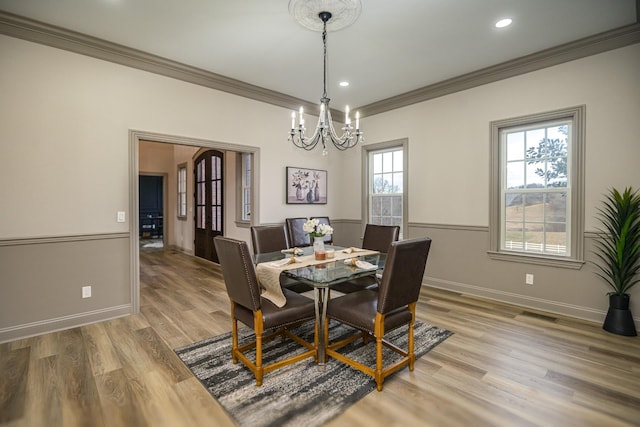 dining space with hardwood / wood-style flooring, ornamental molding, and a chandelier