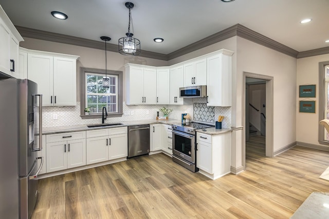 kitchen with sink, appliances with stainless steel finishes, light stone counters, white cabinets, and decorative light fixtures
