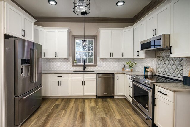 kitchen with high end appliances, white cabinets, sink, and pendant lighting