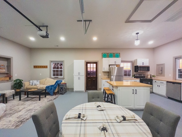 interior space featuring white cabinetry, stainless steel appliances, butcher block countertops, and hanging light fixtures
