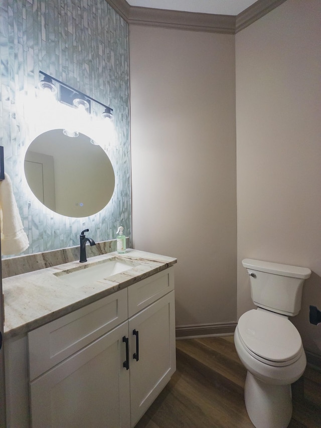 bathroom featuring vanity, crown molding, wood-type flooring, and toilet