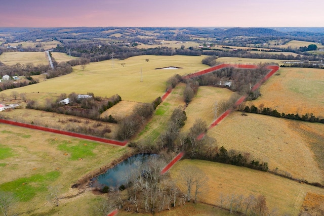 aerial view at dusk with a rural view and a water view