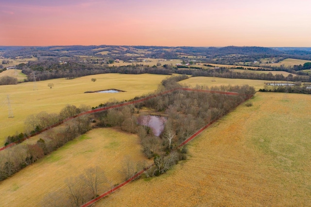 aerial view at dusk featuring a rural view and a water view