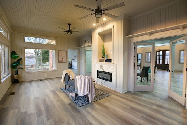interior space with wood ceiling, light hardwood / wood-style flooring, a fireplace, ornamental molding, and french doors