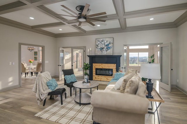 living room with beamed ceiling, a stone fireplace, coffered ceiling, and light hardwood / wood-style floors