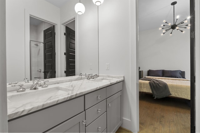 bathroom with hardwood / wood-style flooring, vanity, an inviting chandelier, and a shower