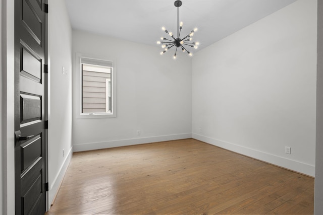 unfurnished room with hardwood / wood-style flooring and a chandelier