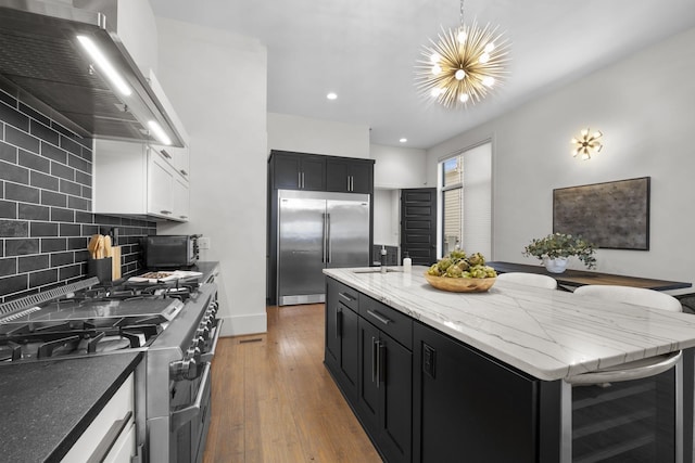 kitchen with decorative light fixtures, sink, a center island, stainless steel appliances, and wall chimney exhaust hood