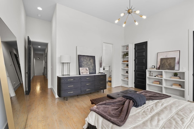 bedroom with a chandelier, a high ceiling, and light wood-type flooring