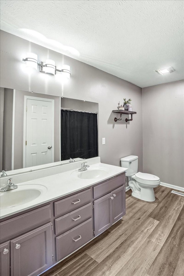 bathroom featuring hardwood / wood-style floors, vanity, toilet, a textured ceiling, and a shower with curtain