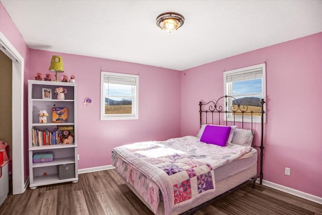 bedroom with dark hardwood / wood-style flooring and multiple windows