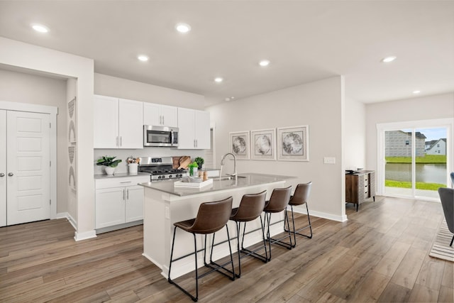 kitchen featuring a breakfast bar, white cabinetry, sink, a kitchen island with sink, and stainless steel appliances