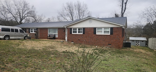 view of front of property featuring cooling unit, a storage unit, and a front lawn