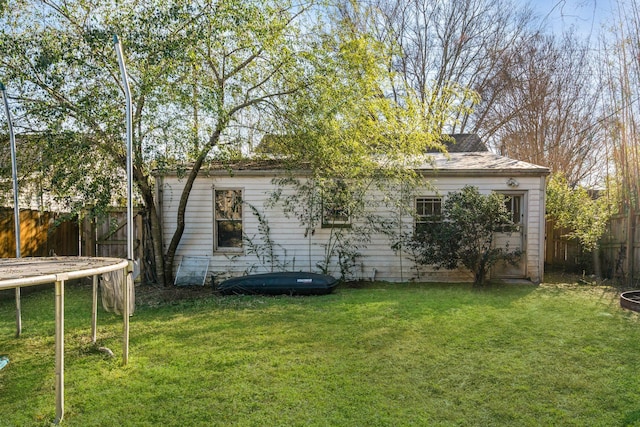 rear view of property with a yard and a trampoline