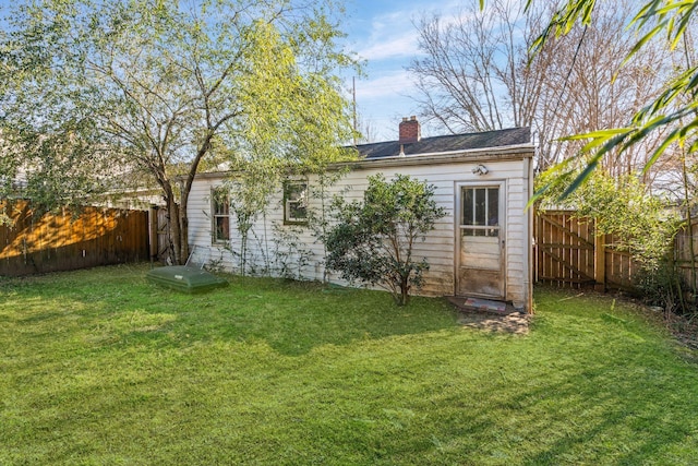 back of property with a yard and an outdoor structure