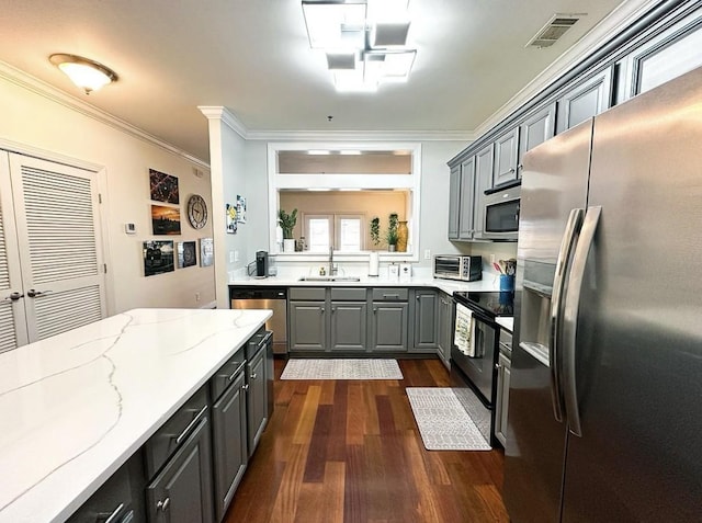 kitchen with crown molding, appliances with stainless steel finishes, gray cabinetry, and light stone counters