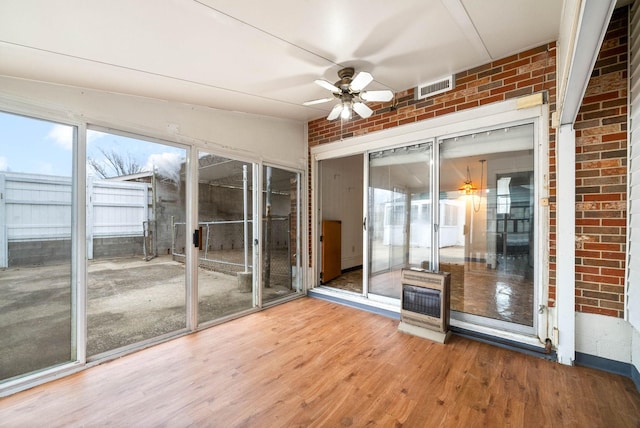 unfurnished sunroom with heating unit and ceiling fan