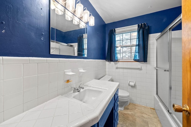 full bathroom featuring vanity, tile walls, shower / bath combination with glass door, and toilet