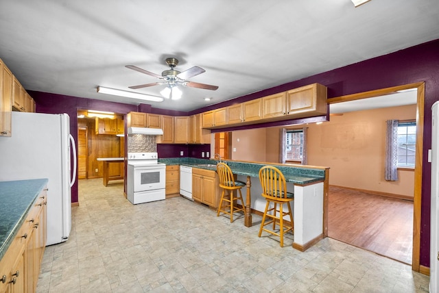 kitchen with sink, white appliances, a kitchen breakfast bar, kitchen peninsula, and ceiling fan