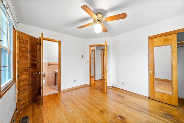 unfurnished bedroom with connected bathroom, tile walls, and light hardwood / wood-style flooring