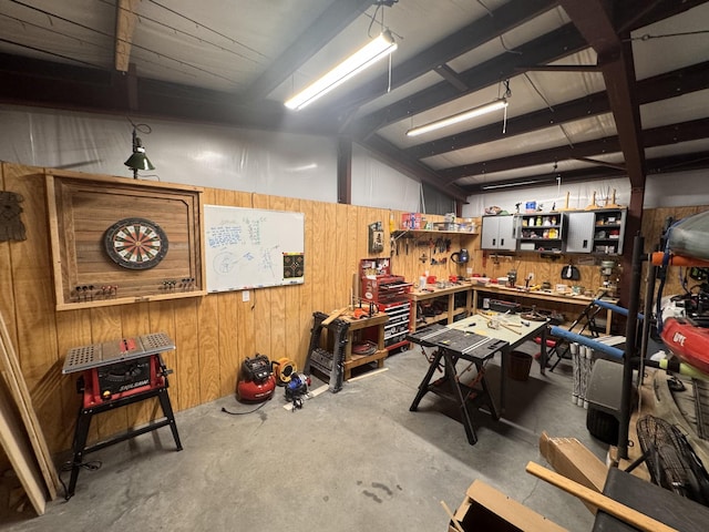 interior space featuring wood walls, concrete floors, and a workshop area