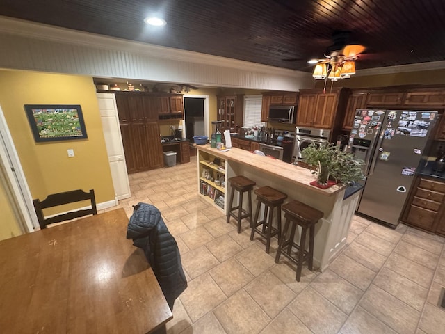 kitchen featuring wood ceiling, ceiling fan, appliances with stainless steel finishes, dark brown cabinetry, and a kitchen bar