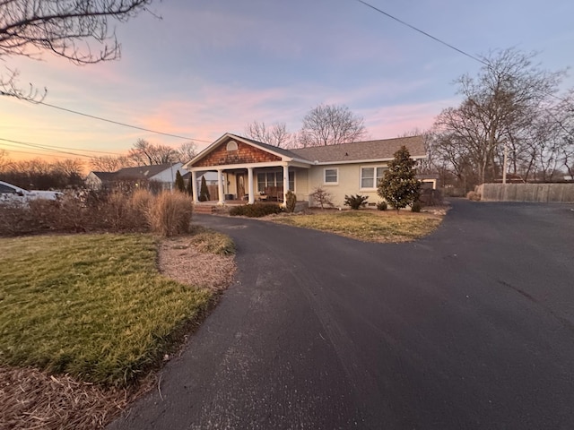 view of front of property with a porch, a front lawn, and aphalt driveway