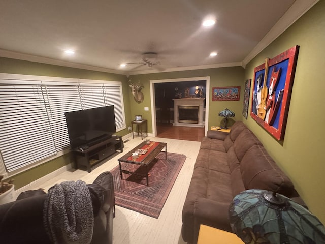 living area with crown molding, a fireplace, recessed lighting, a ceiling fan, and baseboards