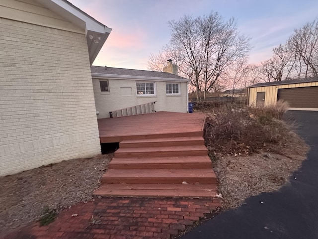 deck at dusk featuring an outbuilding