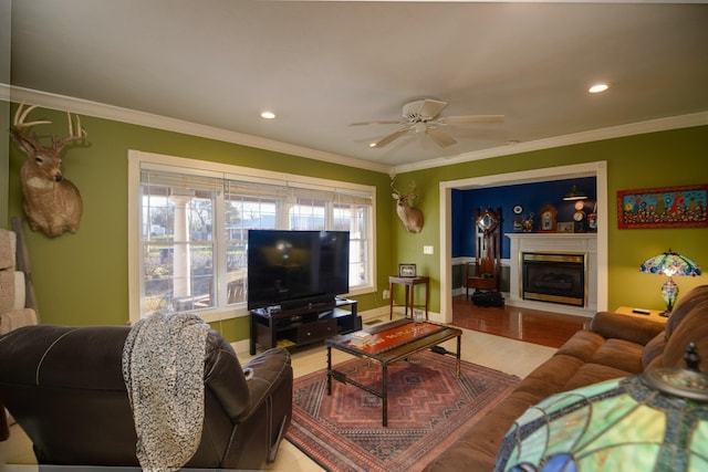 living room with baseboards, a ceiling fan, a glass covered fireplace, ornamental molding, and recessed lighting