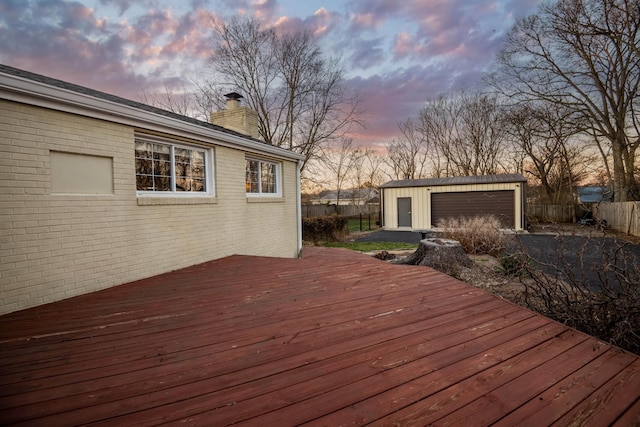 wooden deck featuring a garage, an outbuilding, and fence