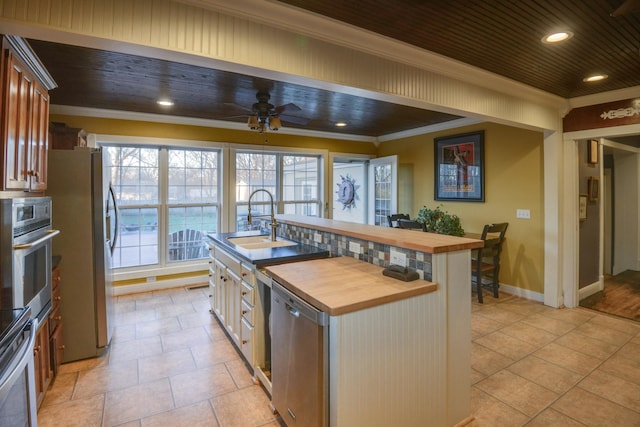 kitchen with a sink, appliances with stainless steel finishes, wooden counters, and crown molding