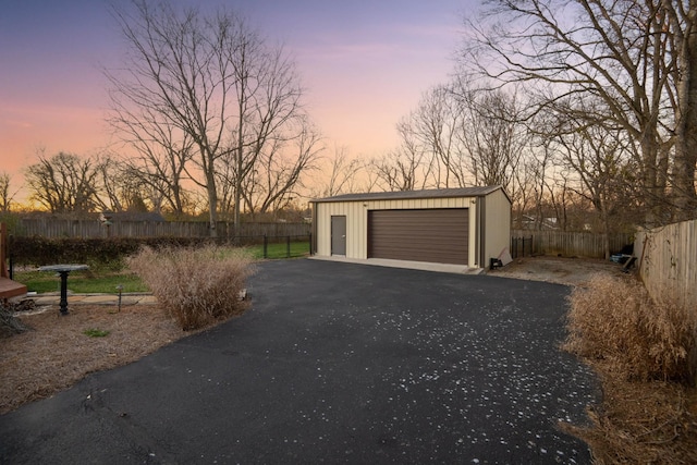 detached garage featuring aphalt driveway and fence