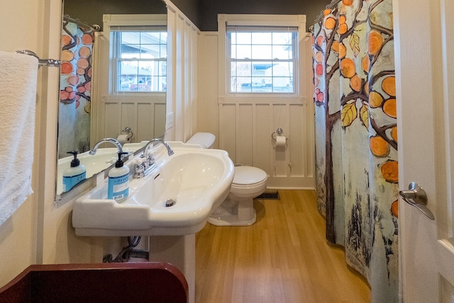 bathroom with curtained shower, visible vents, toilet, a sink, and wood finished floors