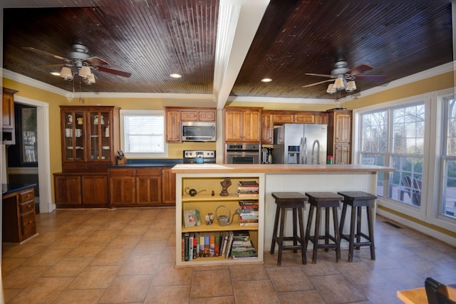 kitchen featuring stainless steel appliances, wooden ceiling, brown cabinets, and ornamental molding