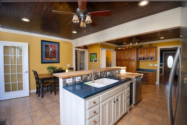 kitchen with a kitchen island with sink, a sink, wood ceiling, freestanding refrigerator, and crown molding