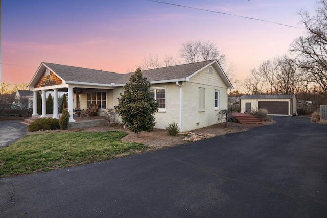 view of front of house with a garage, covered porch, brick siding, an outdoor structure, and crawl space