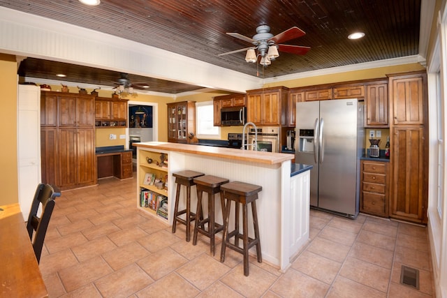 kitchen featuring brown cabinets, crown molding, a center island with sink, stainless steel appliances, and visible vents